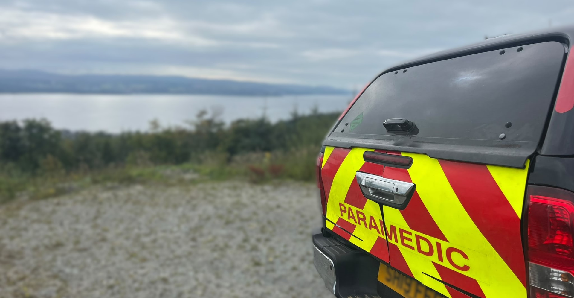 Alba EMS 4x4 paramedic response vehicle parked on a gravel track above a Scottish sea loch