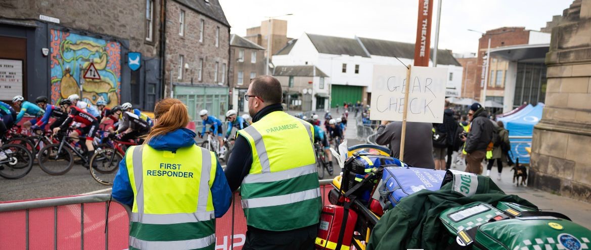 Two Alba EMS staff observing a cycle race passing through an urban street