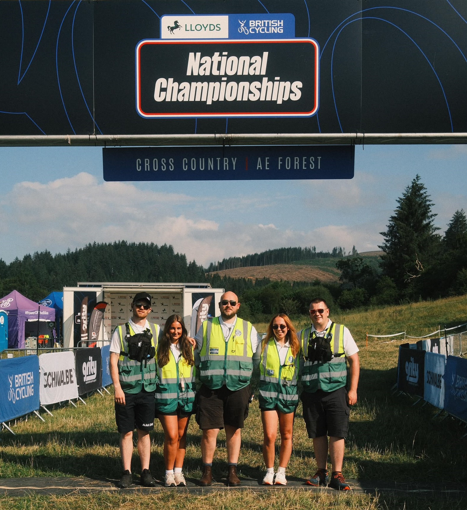 Alba EMS clinicians in high-visibility vests beneath a National Championships finish line banner